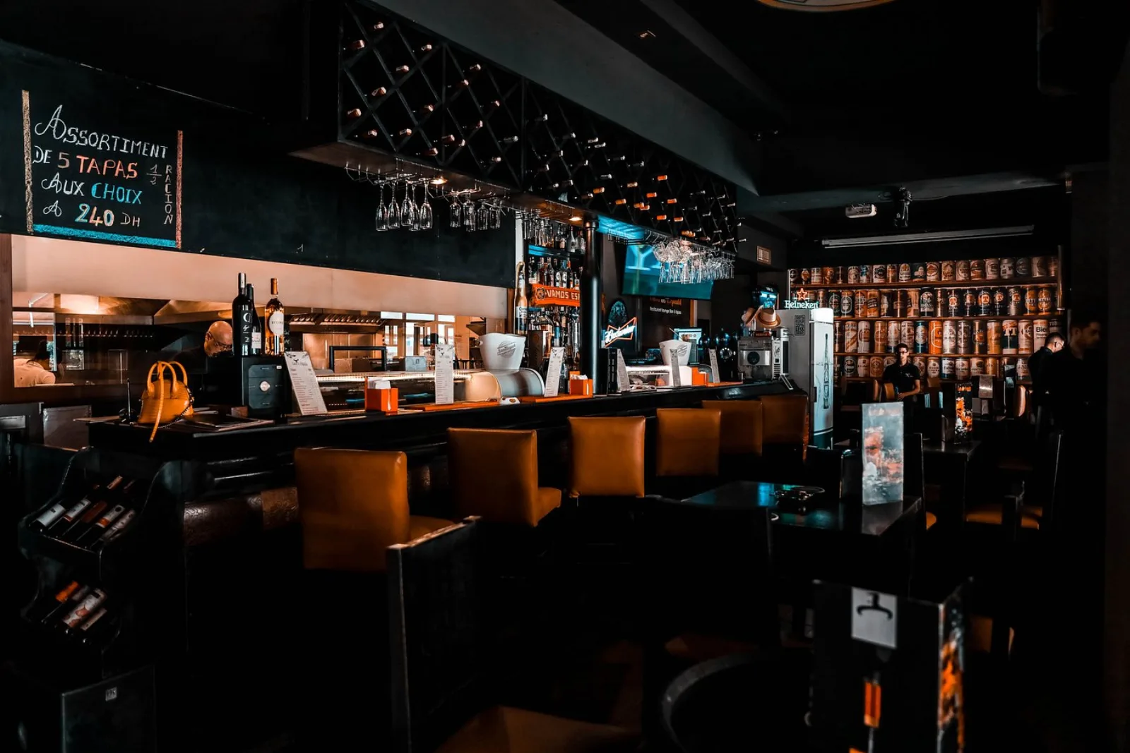 Le bar de Casa de España — cave à vins, mur de bières, tabourets